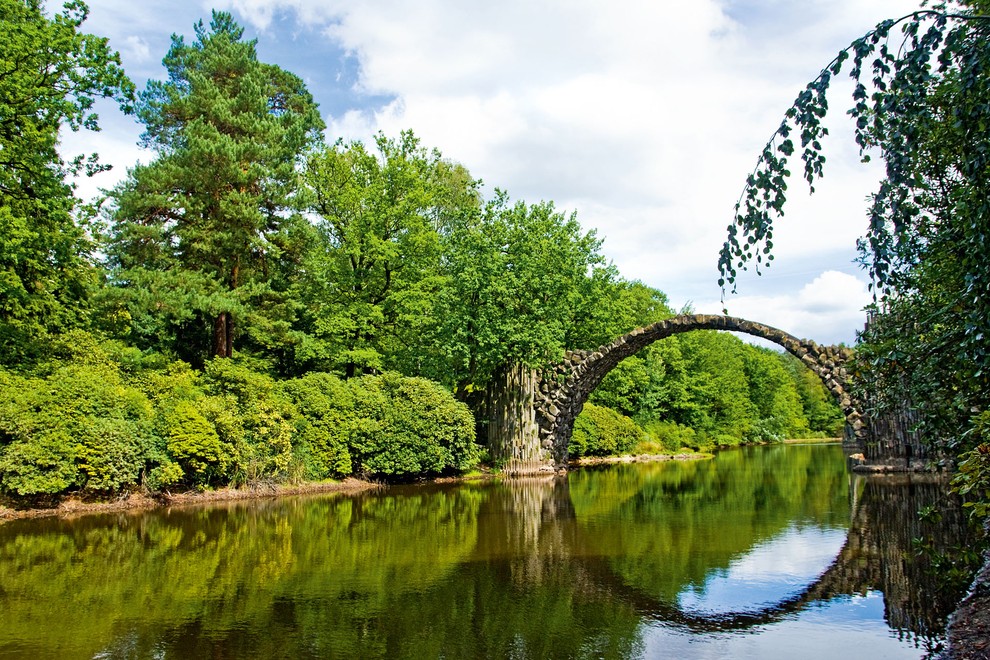 MOST RAKOTZBRÜCKE ALI HUDIČEV MOST, GÖRLITZ, NEMČIJA Most je v 81 hektarjev velikem parku Azaleen- und Rhododendronpark Kromlau v Saksoniji, …