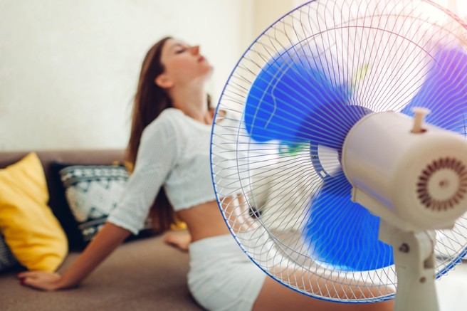 Ženska se hladi z ventilatorjem.