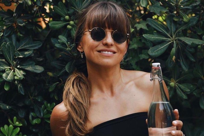 Ženska s steklenico vode v roki.