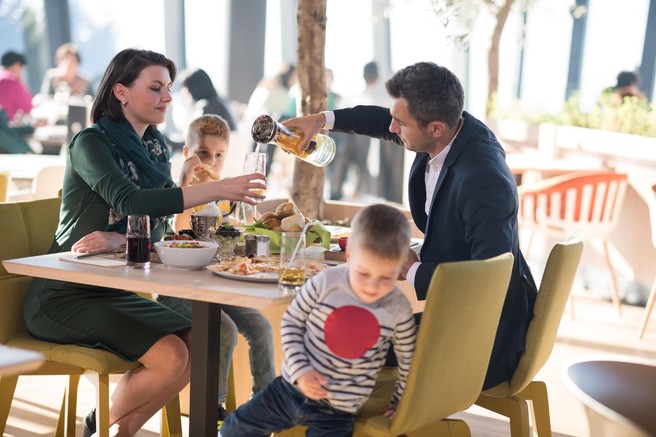 Družina z dvema malima otrokoma obeduje v restavraciji.