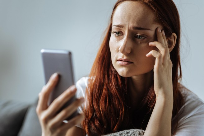 Žalostna ženska gleda v telefon in joče