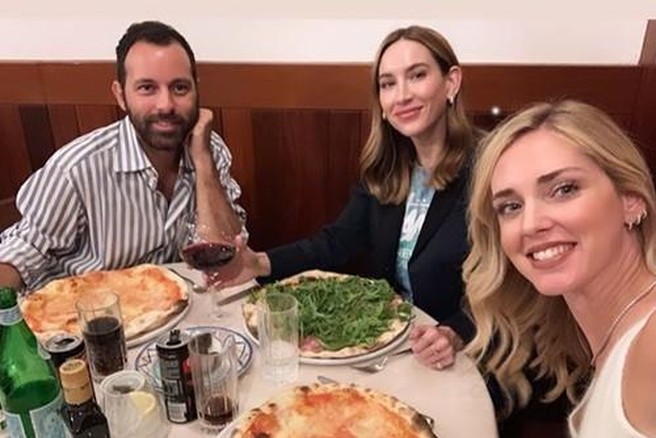 Skupina prijateljev obeduje pizzo v restavraciji.
