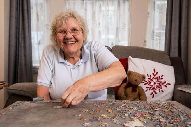 Starejša ženska sestavlja puzzle.