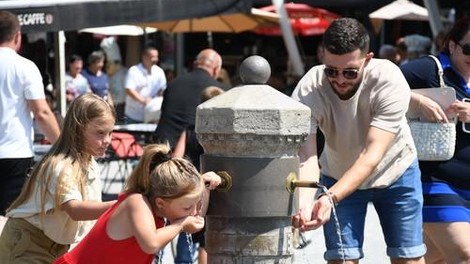 Moški in dve mlajši ženski se odžejajo sredi mesta ob visoki temperaturi.