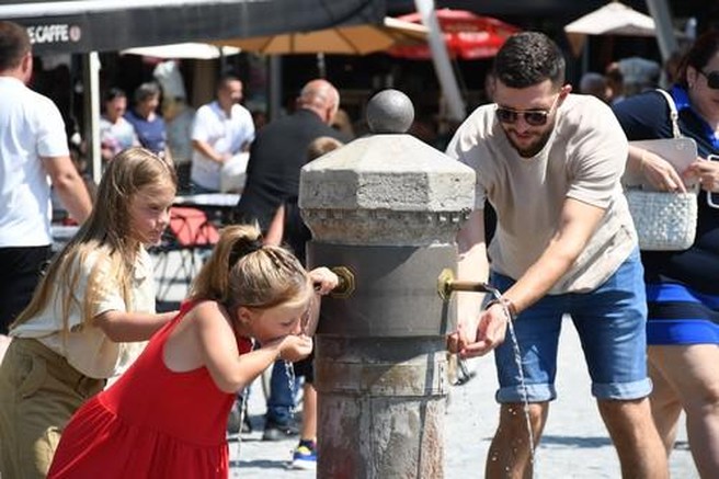 Moški in dve mlajši ženski se odžejajo sredi mesta ob visoki temperaturi.