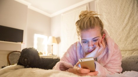 Ženska v postelji uporablja telefon
